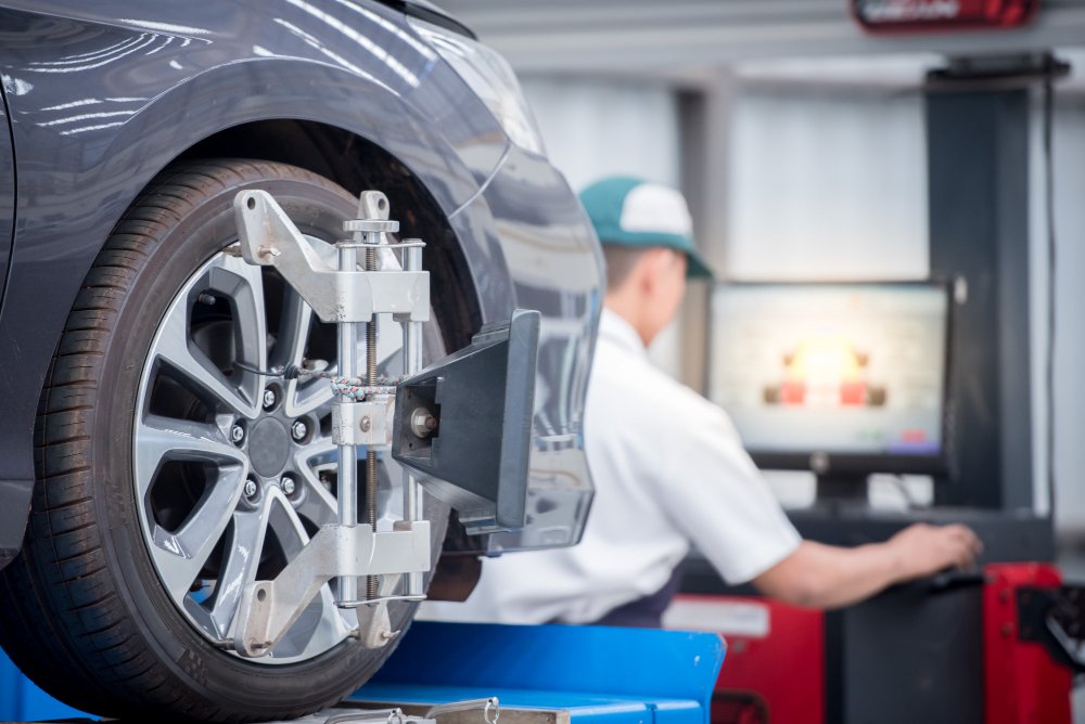 Using specialized tools, a mechanic aligns the wheels of an automobile to change the wheel angles.